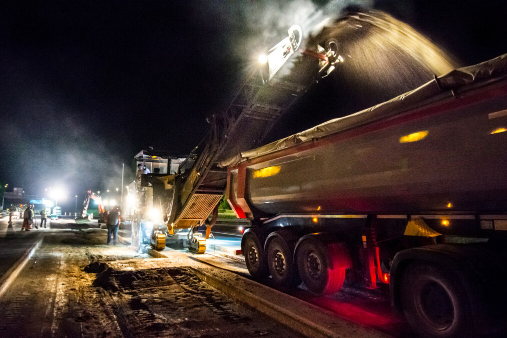 GoPique night milling operation with tipper truck receiving reclaimed asphalt under work lights